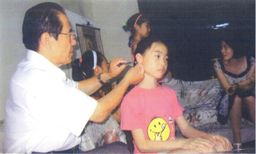 孙鸿理大夫给患有近视眼的学生进行“耳穴埋豆”治疗